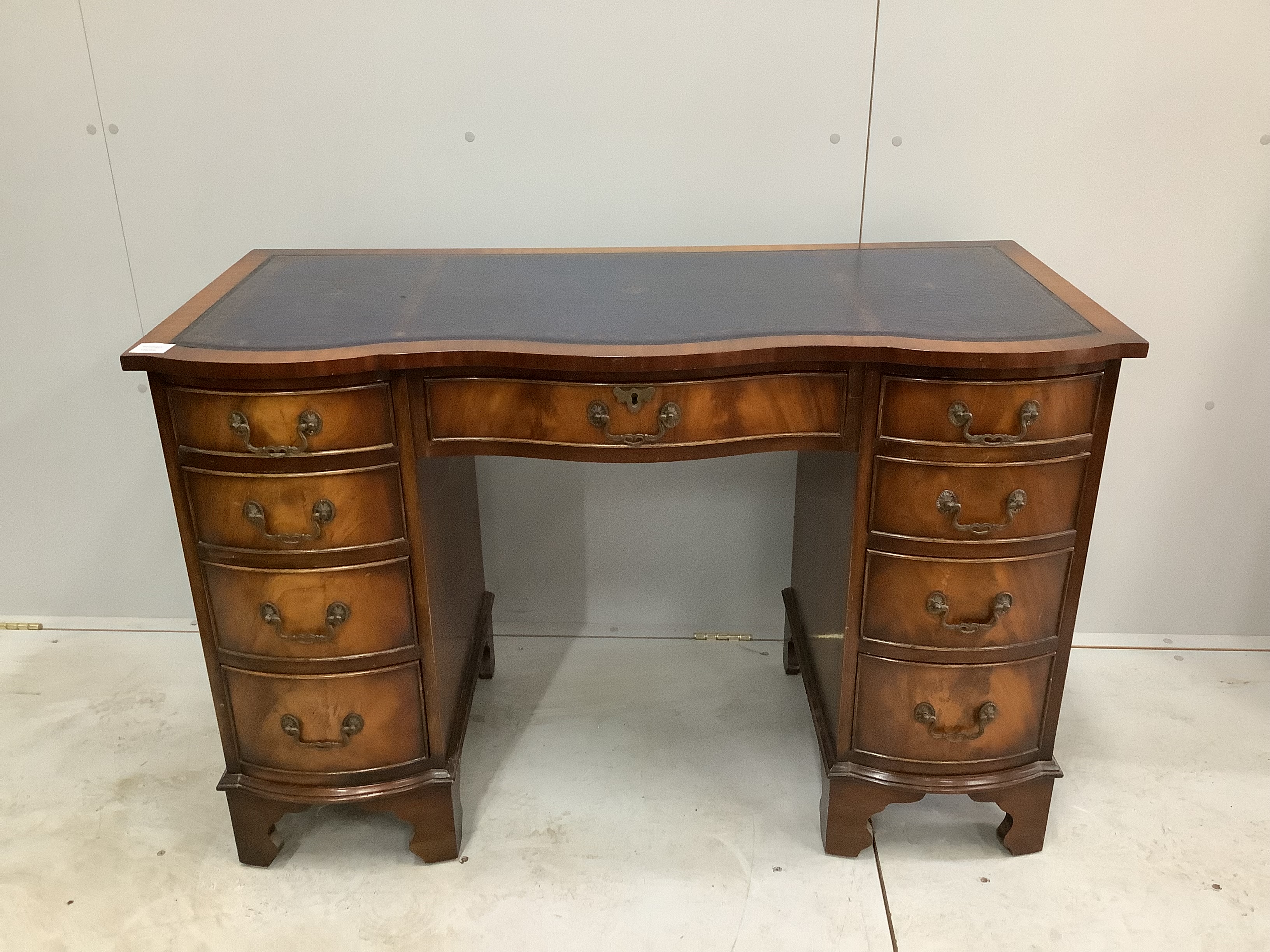 A reproduction George III style serpentine mahogany kneehole desk, width 115cm, depth 53cm height 76cm